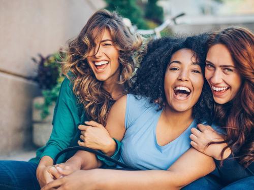 Three young women laughing outdoors